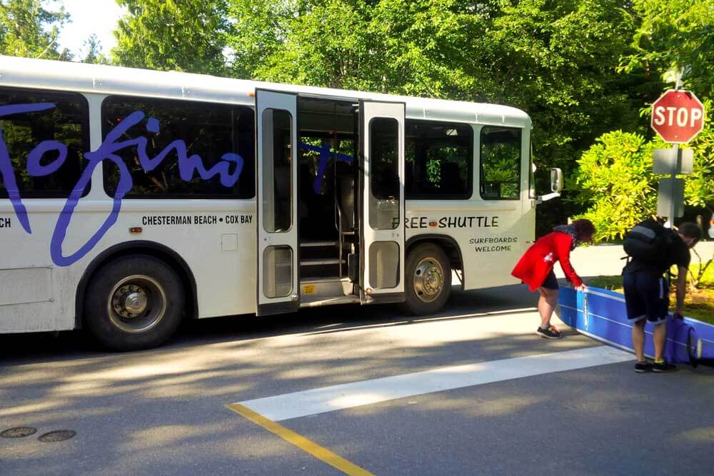 Two people load a surfboard on the free shuttle in Tofino