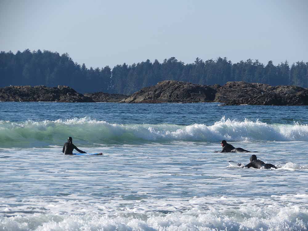 3 surfers paddling out through waves